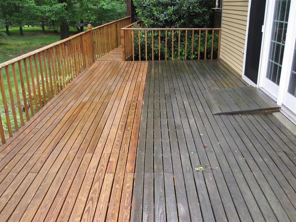 A deck half cleaned, showing the sharp line between restored golden boards and the gray weathered surface still to be done